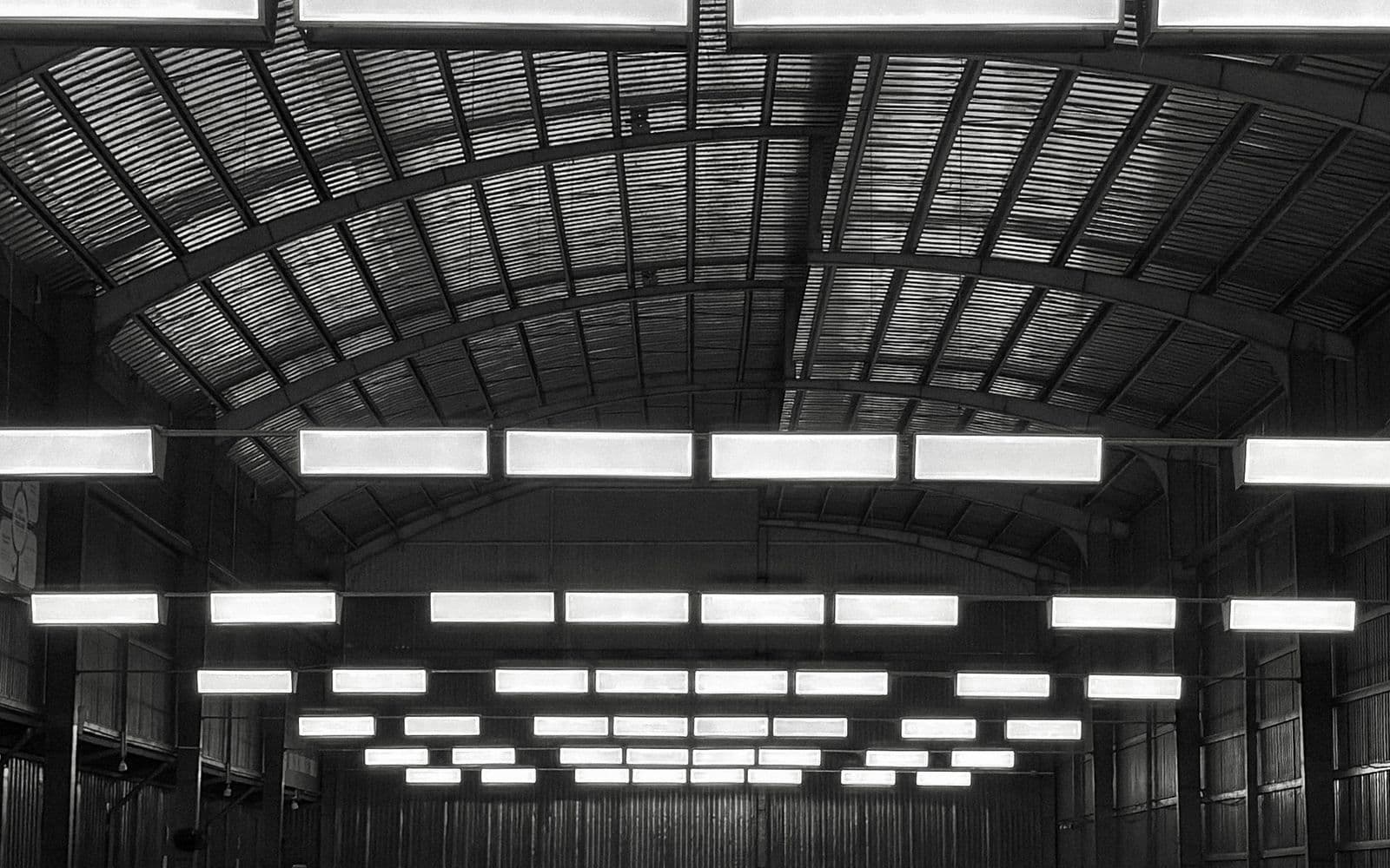Atmospheric black-and-white view of a busy indoor badminton court with players mid-rally