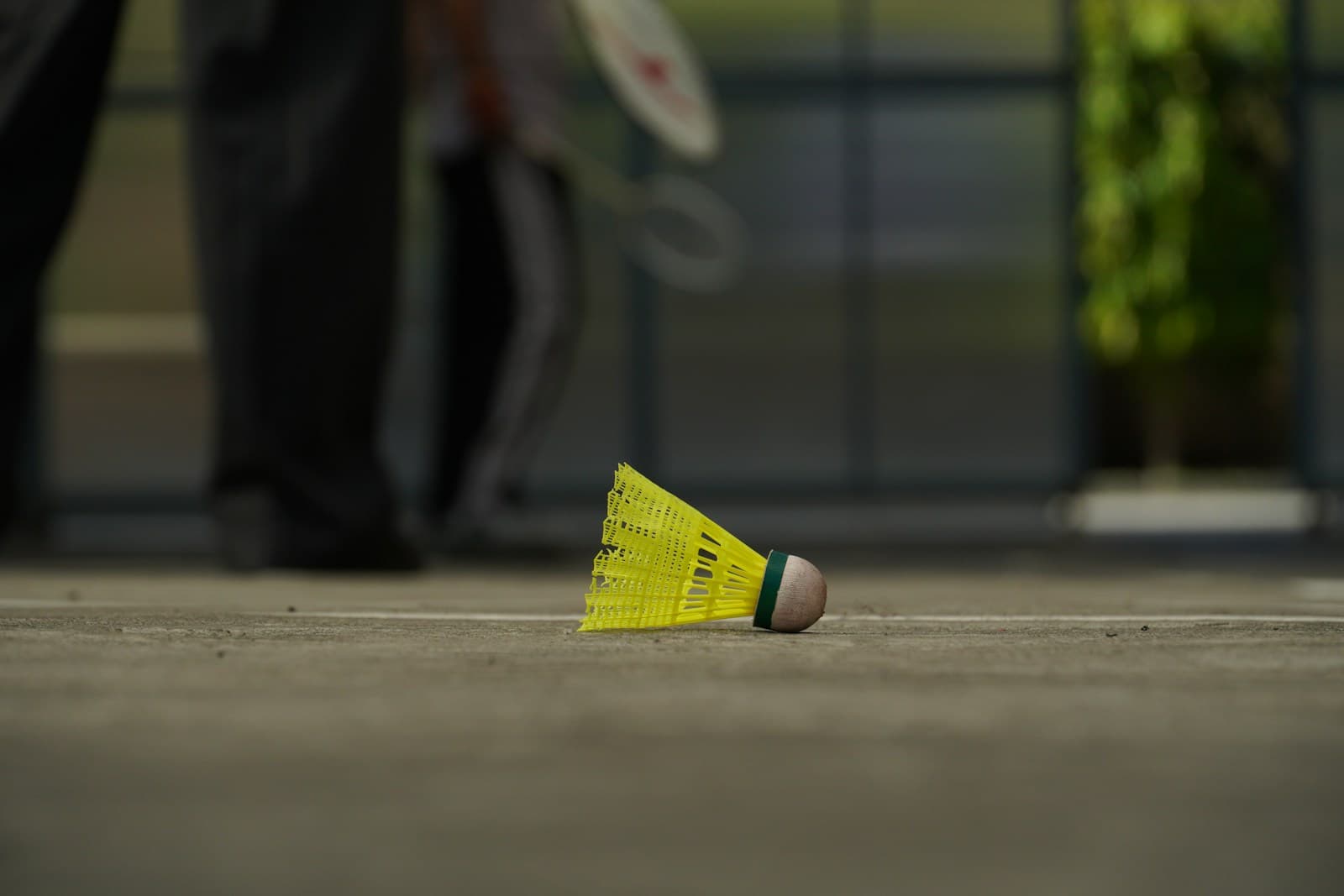 Yellow shuttlecock resting on the court line with blurred player footwork in the background