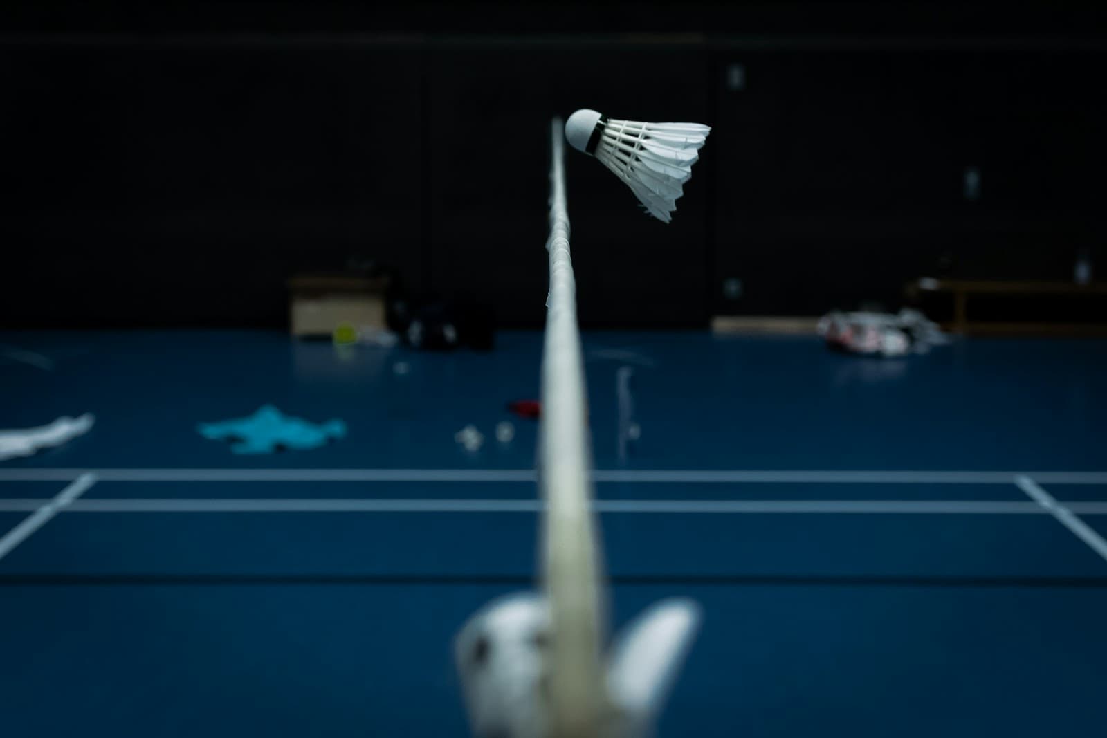 A white badminton shuttlecock in mid-flight against an indoor court background