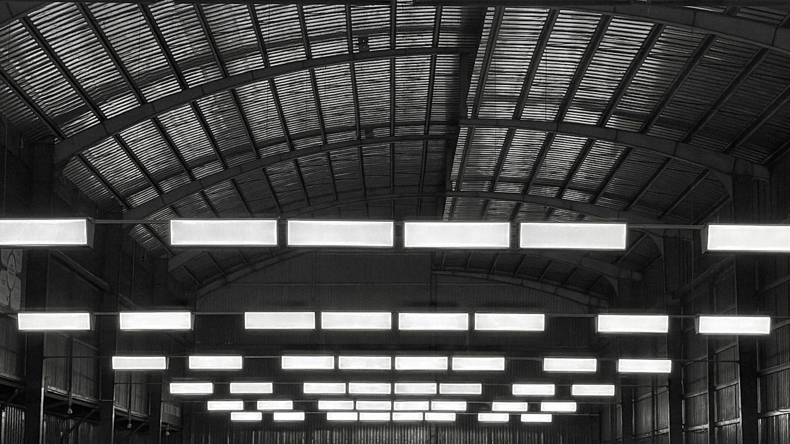 Monochrome wide-angle view of an indoor badminton hall with court markings and players blurred in the background